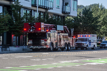 Fototapeta na wymiar fire truck ladder co company and ambulance with flashing lights at emergency near downtown apartment building
