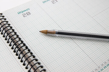 Close-up of a pen on an agenda in Catalan with the 20th and 21st on empty pages