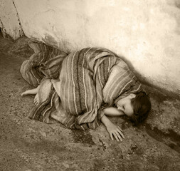 A girl in poor clothes lies on the ground