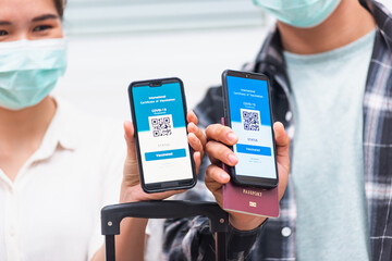 Asian young couple woman and man ready to travel showing digital vaccine health passport certificate app in smartphone screen during coronavirus pandemic, Mobile app of virus covid-19 vaccination