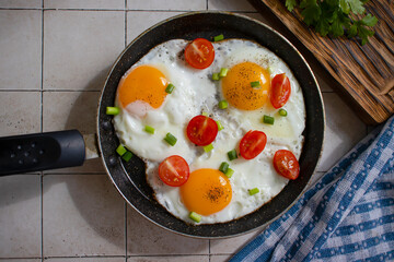 Fried eggs with tomatoes in a pan