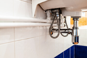 new white polypropylene pipes connect with faucet under sink in bathroom on wall covered with...