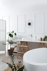 Fototapeta na wymiar Interior of light bathroom with white sink, bathtub and houseplants
