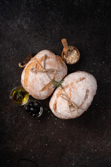 Freshly baked sourdough ciabatta bread with olives and rosemary on a black rustic table. Artisan bread