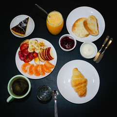 Restaurant breakfast, coffee, croissant, orange juice, toast, jam, fruits and chocolate cake