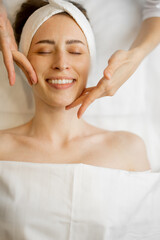 Adult woman receiving relaxing facial massage, close-up view from above on woman's face during a massage. Beautiful pose of masseur's fingers