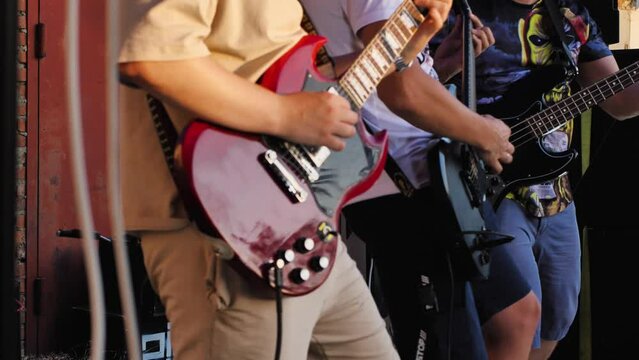 Two guitarists and a bass player playing on the same stage at a concert. A rock band performing at an open-air festival. Close-up