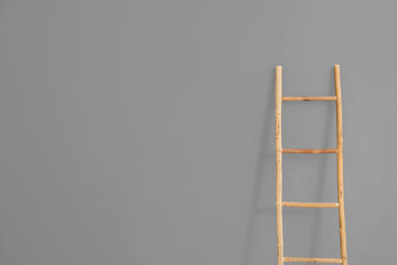 Wooden ladder near grey wall in room