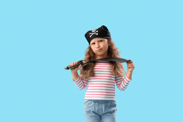 Cute little girl dressed as pirate with sword on blue background