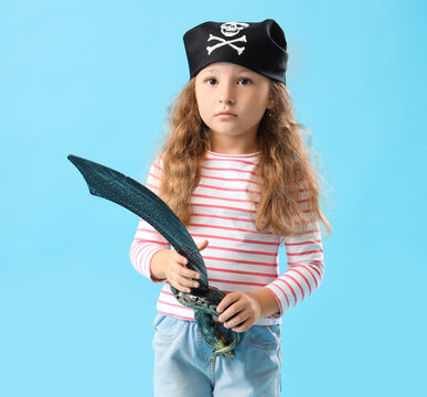 Cute little girl dressed as pirate with sword on blue background