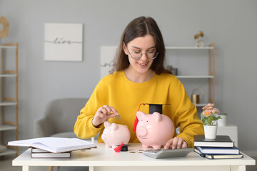 Happy female student calculating finances and putting coin in piggy bank. Student loan concept