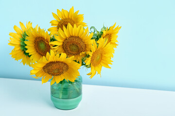 Vase with sunflowers on shelf near blue wall