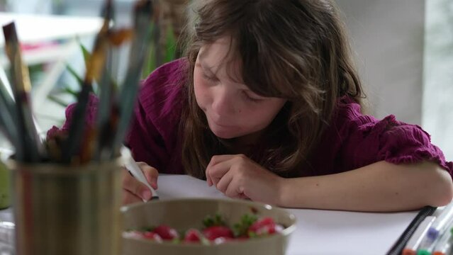 A Little Girl Sits at the Table and Draws with Paints, Pencils and Felt Tip Pens