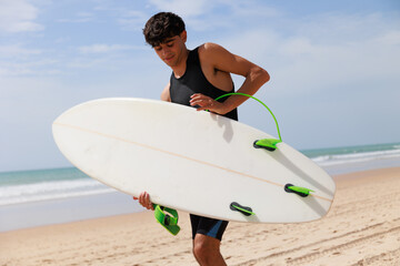 Joven surfista en la playa con tabla de surf 