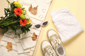 Fototapeta na wymiar Beautiful autumn composition with stylish clothes, leaves and bouquet of flowers on beige background