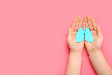 Female hands holding paper lungs on pink background. Lung cancer concept