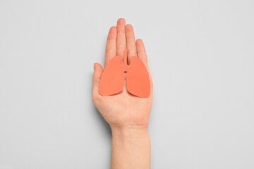 Female hand with paper lungs on grey background. Lung cancer concept