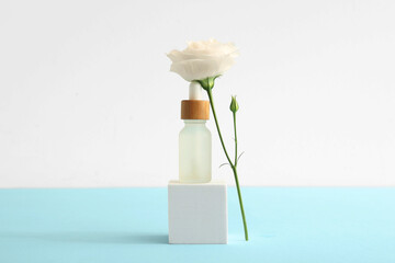 Composition with bottle of essential oil, plaster podium and beautiful eustoma flower on color background