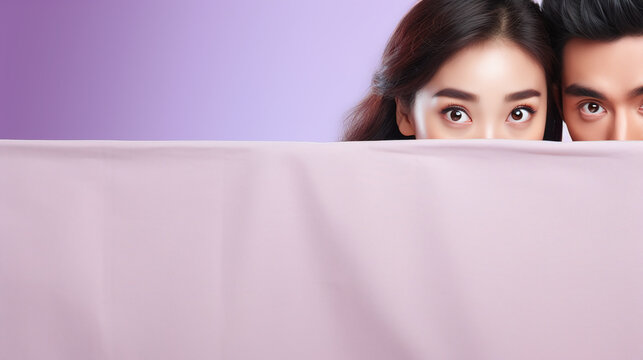 text space for advertising with funny part as portrait of black haired asian couple models peeking over a colored panal