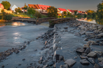 Big weir in Budweis with blue sky and countryside buildings in sunset evening