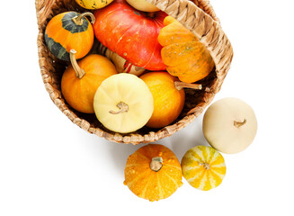 Wicker basket with different fresh pumpkins on white background