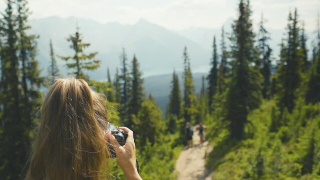 A woman are taking a picture, in the forest at the Bald Hills trail, in the stunning landscape of Jasper National Park in Canada, overlooking the Maligne Lake