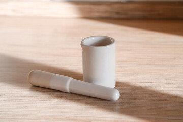 White porcelain kitchen mortar and pestle on the table on a sunny day