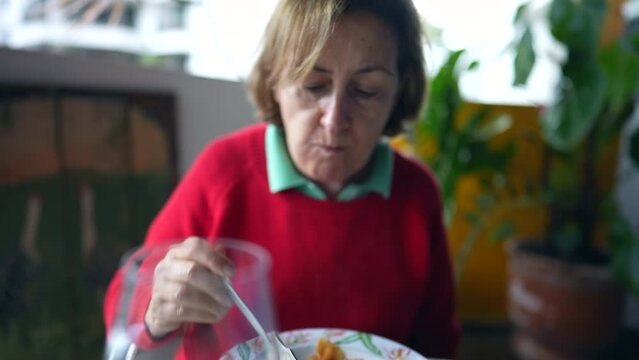 Senior woman eating pasta food at balcony, elderly lady enjoying mealtime lunch, carb food