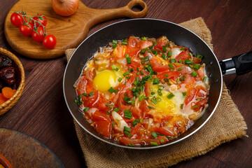 hot shakshuka in a frying pan sprinkled with green onions on the Shabbat table.
