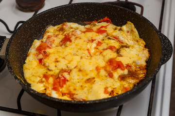 Shakshuka with tomatoes and sweet cheese sprinkled in a frying pan on the stove
