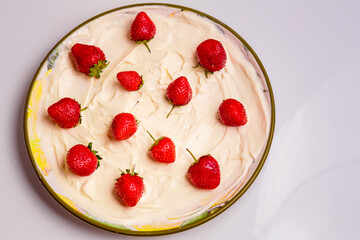 Fresh juicy strawberries in whipped cream in a plate.