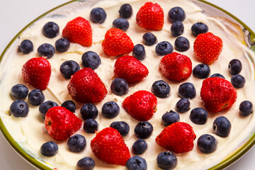 Fresh juicy strawberries and blueberries blueberries in heavy whipped cream in a plate