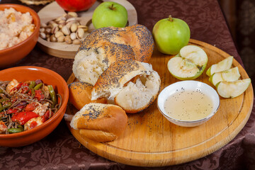 Festive set table for Rosh Hashanah with ritual treats honey challah apple on brown tablecloth.