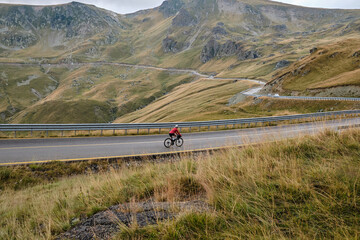 Fototapeta premium Man riding gravel bike on gravel road in mountains with scenic view.Cyclist riding on gravel bike.Cyclist practicing on gravel road.Man cyclist wearing cycling kit and helmet.Alicante region in Spain.