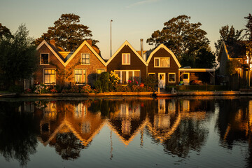 Obraz premium Traditional style Dutch architecture houses reflecting off the still water of the Oude Rijn river in the morning golden hour. riverside lifestyle with natural beauty for living comfort 