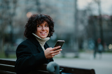 Young girl sitting on a bench while looking onto the distance with a smile.