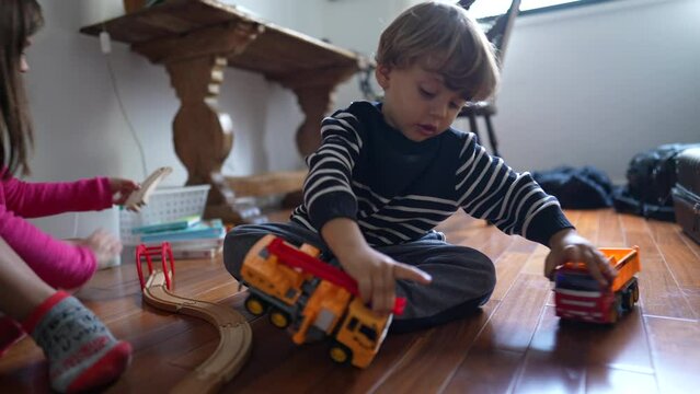 Small boy playing with his truck toys, hitting vehicle cars together. Child engrossed with play at home, male caucasian kid plays with objects