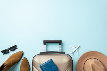 Pack for an autumn escape in sophistication. Gray suitcase with passport, brown boots, sunglasses, and felt hat on light blue isolated background, offering space for your promotional content or text