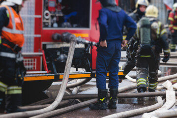 Group of fire men in protective uniform during fire fighting operation in the city streets,...
