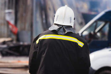 Group of fire men in protective uniform during fire fighting operation in the city streets, firefighters brigade with the fire engine truck vehicle in the background, emergency and rescue service