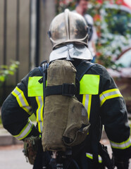 Naklejka premium Group of fire men in protective uniform during fire fighting operation in the city streets, firefighters brigade with the fire engine truck vehicle in the background, emergency and rescue service