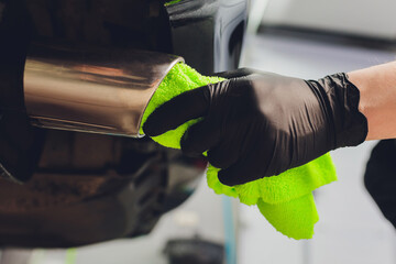 Car exhaust pipe with soap. Car wash background. close-up of a green rag