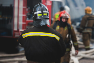 Group of fire men in protective uniform during fire fighting operation in the city streets,...
