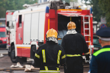 Group of fire men in protective uniform during fire fighting operation in the city streets,...