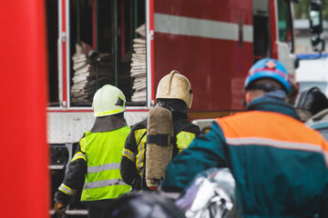 Group of fire men in protective uniform during fire fighting operation in the city streets,...