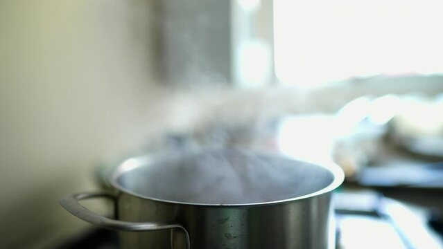 Steam smoke coming from metal pan at kitchen stove, food preparation