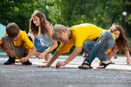 Children drawing with chalk on asphalt