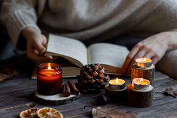 Aromatherapy on a grey fall morning, atmosphere of cosiness and relax. Autumn cozy home composition with hot chocolate with marshmallow and candles. Wooden background, books, close up.