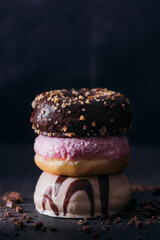 White chocolate donut, pink donut, chocolate donut in a pile