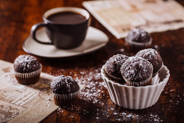 Americano coffee and a little bowl with small chocolate cupcakes